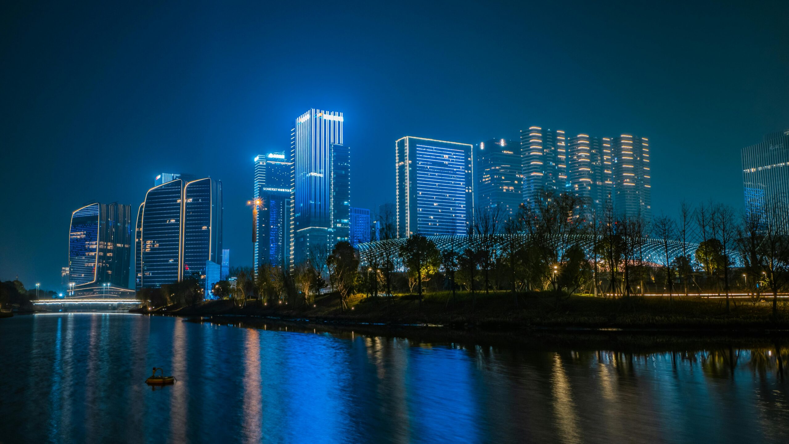 Illuminated skyscrapers reflecting on the water in Hangzhou, China at night.